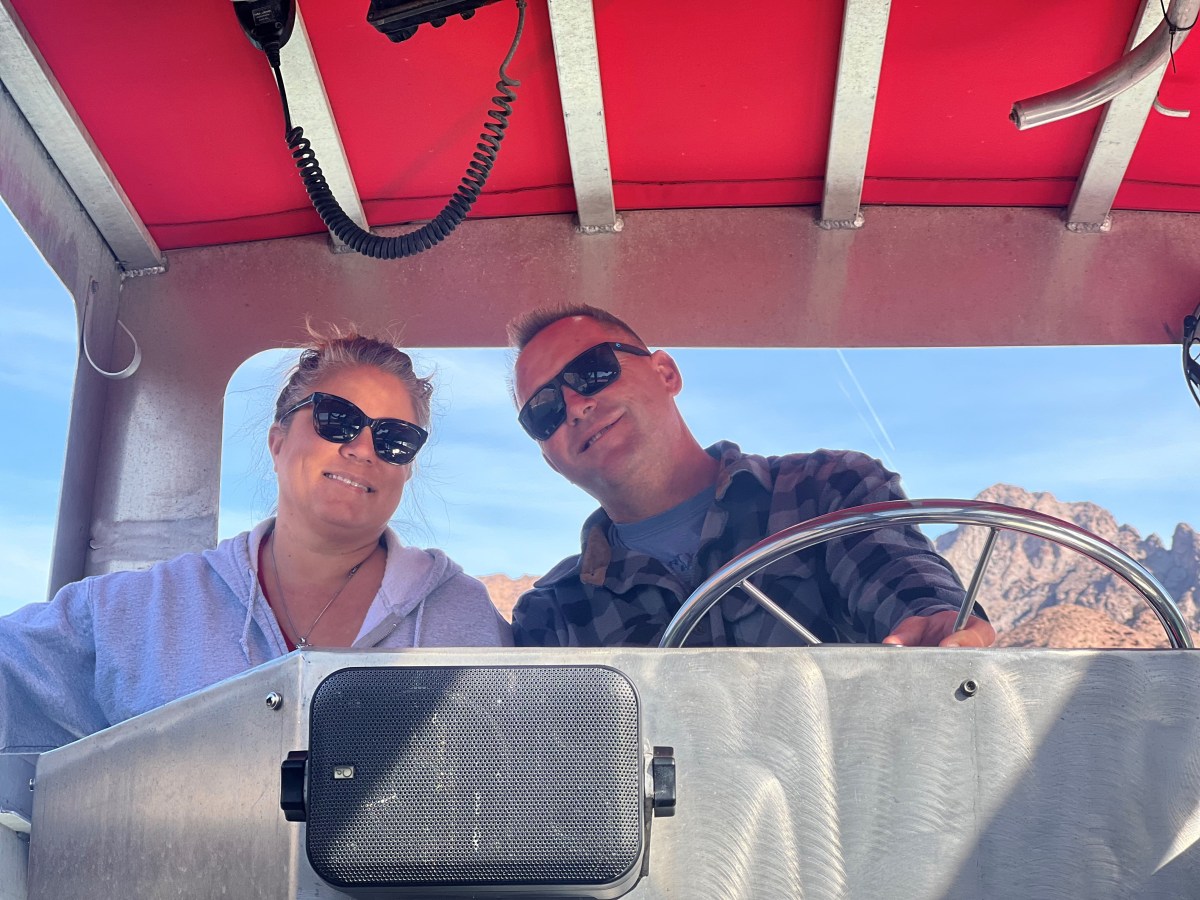 Two people wearing sunglasses on a boat with a red canopy.